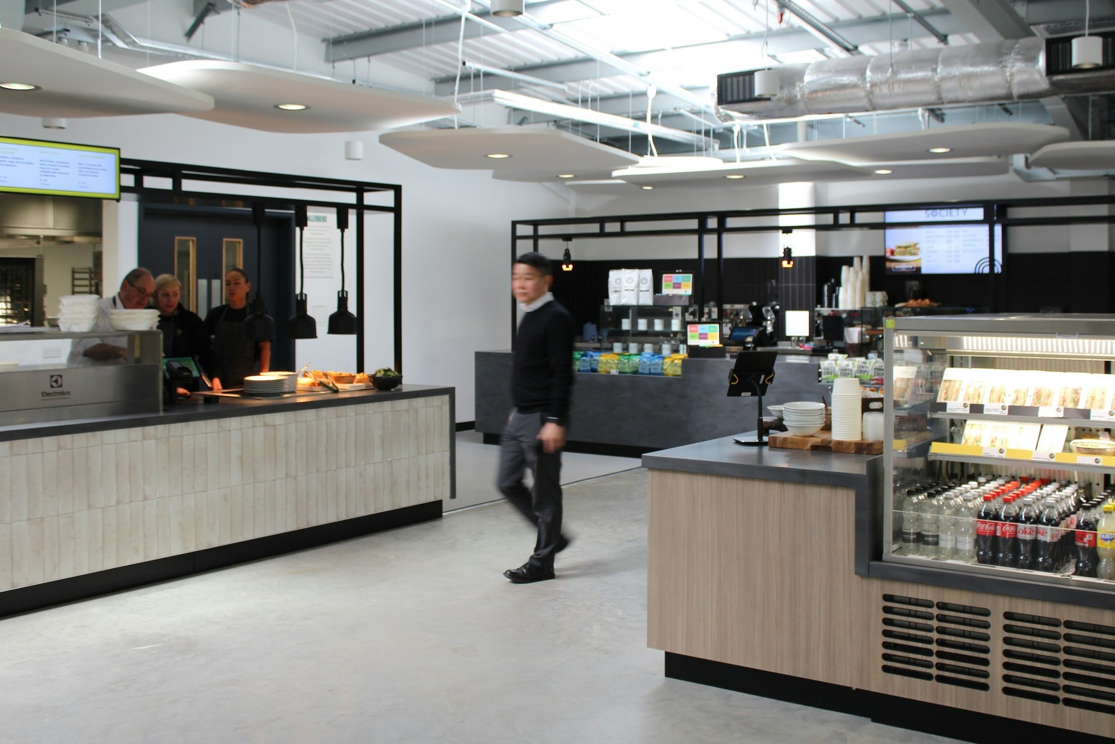 Staff canteen servery with two counters, a chilled drinks display and menu screens