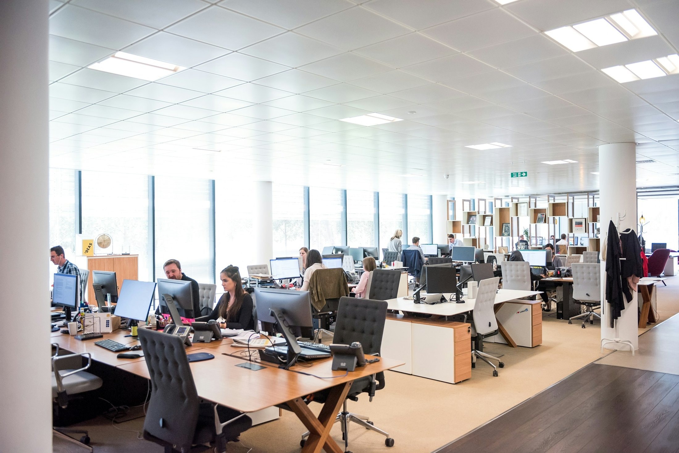 Bright open-plan floor with rows of staff working at desks under ceiling lights