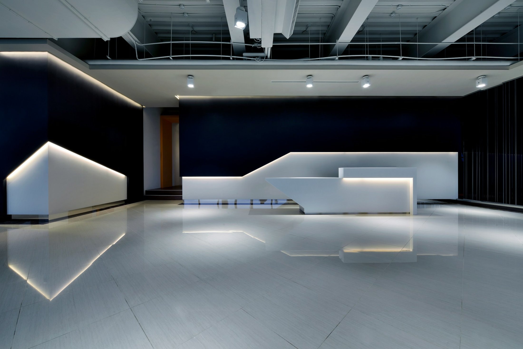 Long white service counter under spotlights in a dark-walled hall