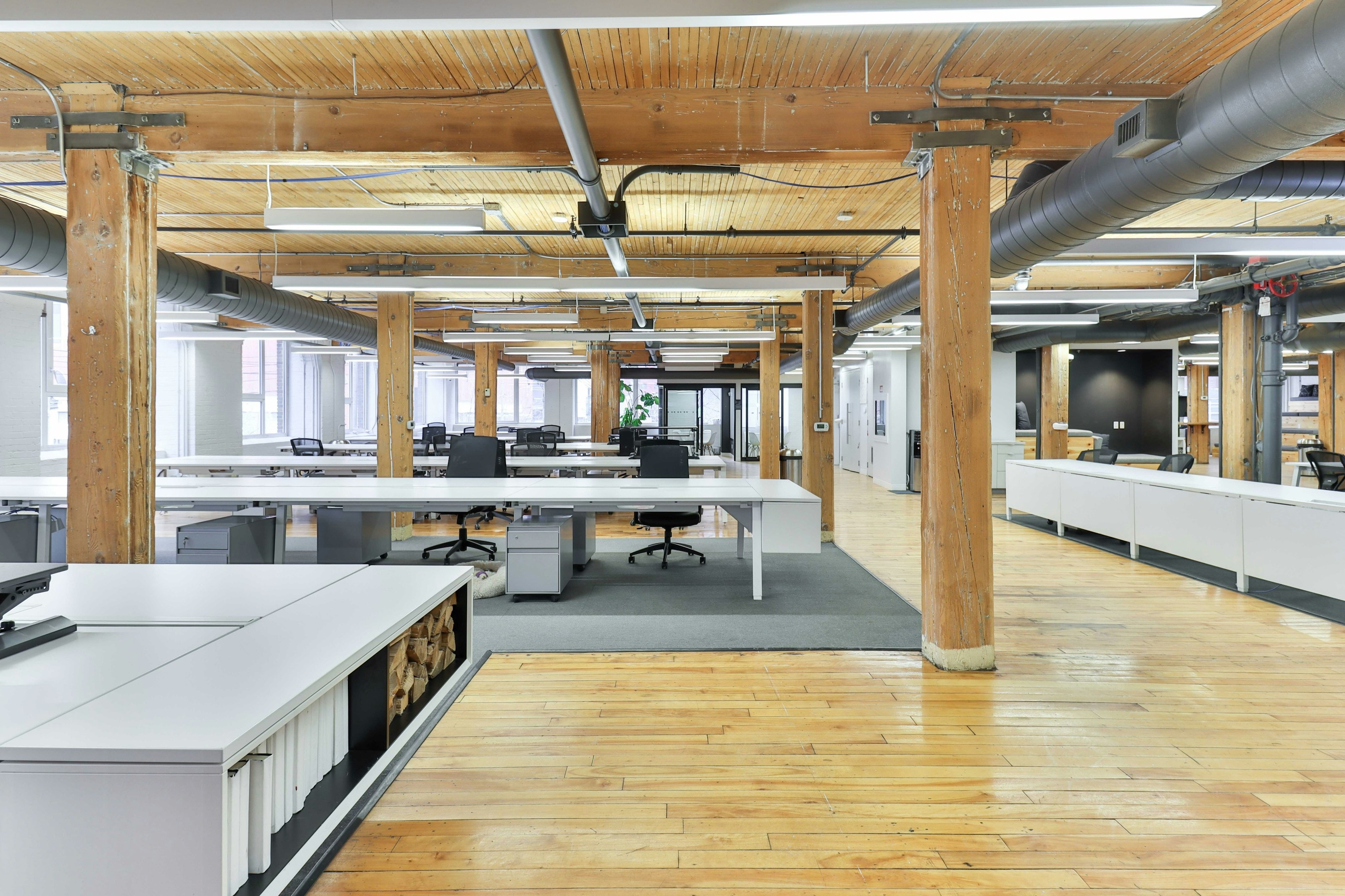 Finished loft office with timber columns, white workstations and exposed ductwork
