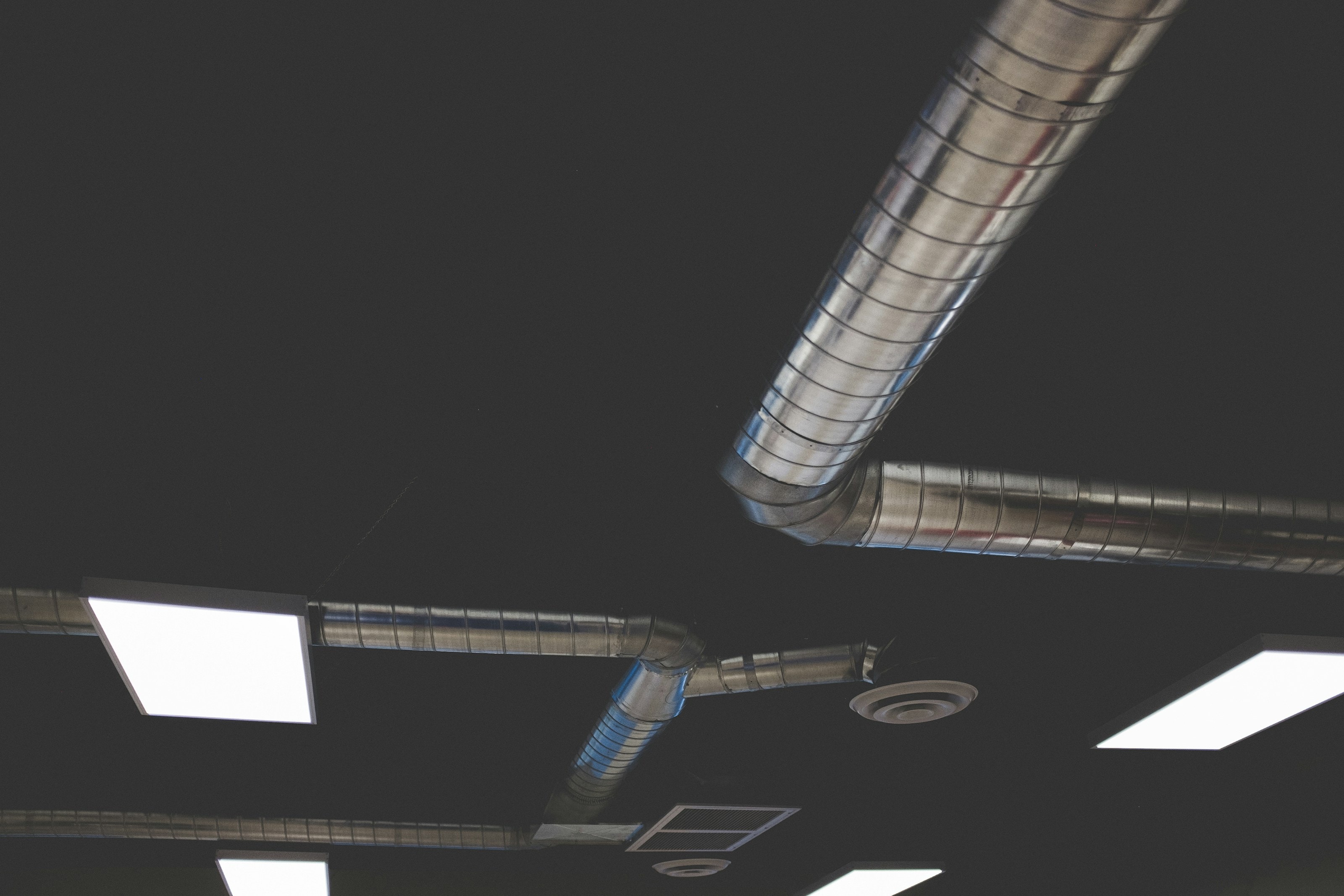Spiral ductwork and ceiling lights in a dark ceiling void